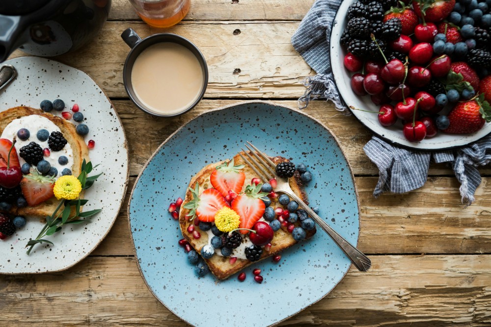 A top down shot of a breakfast on a table with lots of fruit and berries.