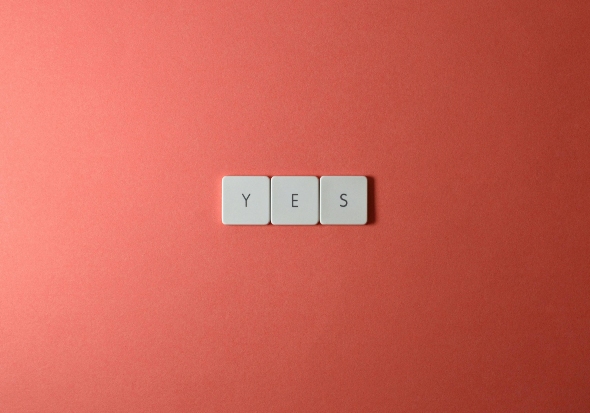 yes spelled with scrabble blocks on a peach background
