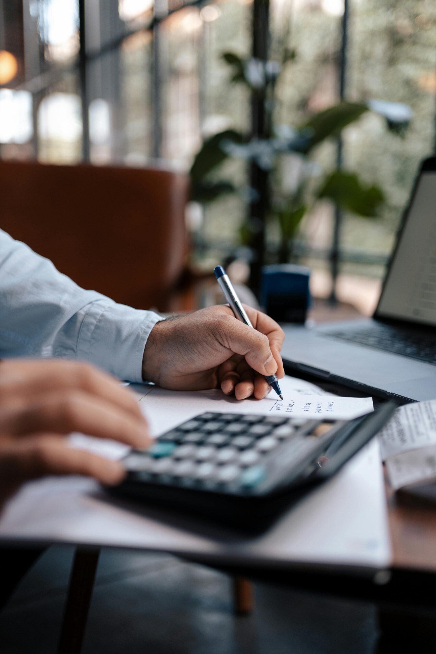A person using a calculator and writing down on a piece of paper