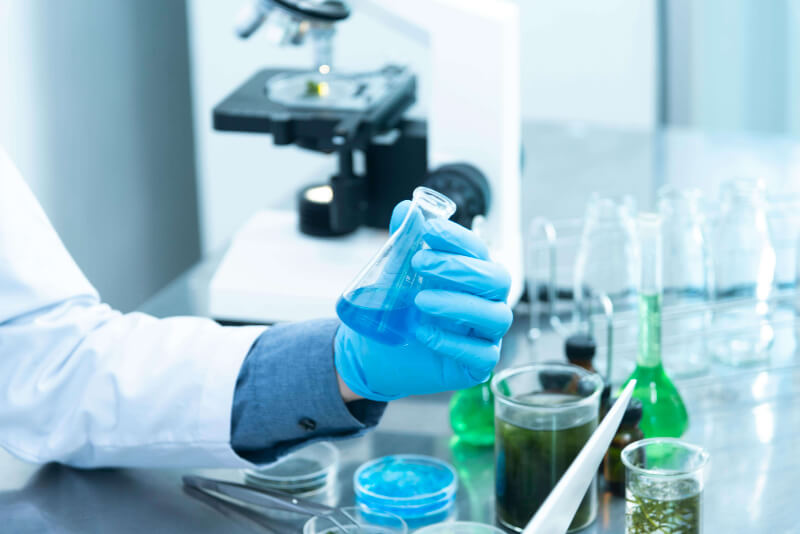 A chemist analysing contents in a flask whilst holding it