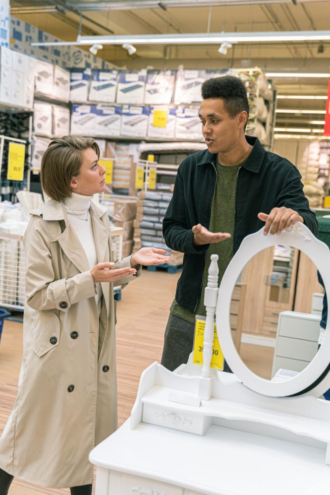 a worker in a show room showing a woman a mirror to buy
