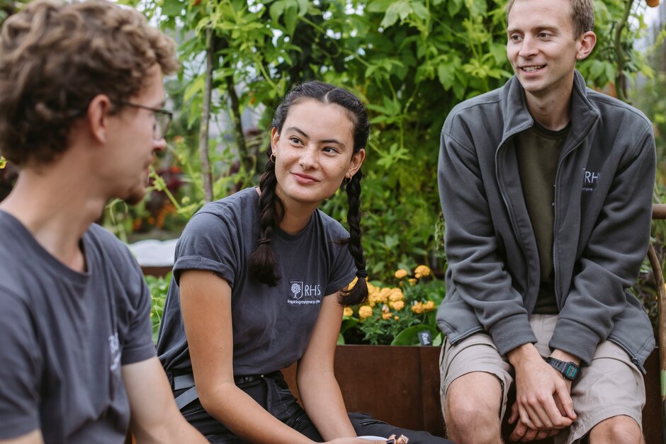 3 RHS students in conversation in a garden.