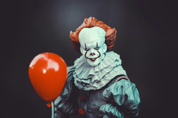 pennywise holding a balloon standing in front of a black background